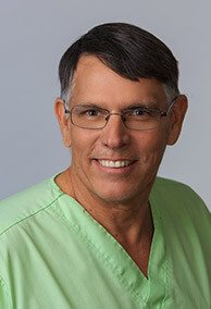 Smiling Dr. W. Keith deJong in green scrubs