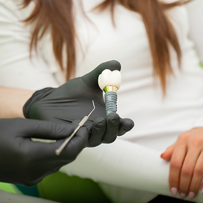 Gloved hands holding dental implant