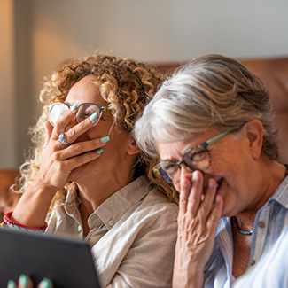 Two women laughing and covering their mouths