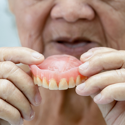 Woman holding a denture in River Ridge