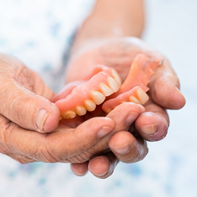 Hands holding full dentures