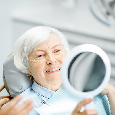 Senior woman checking smile in mirror