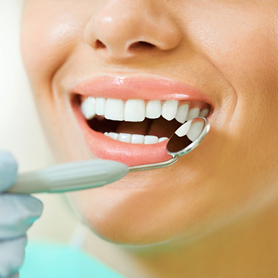 Using mirror to examine a patient's teeth during dental checkup in River Ridge