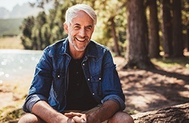 man in nature smiling with dental implants in River Ridge 