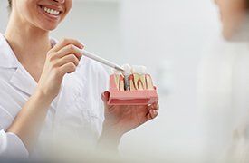 dentist showing a dental implant model to a patient 