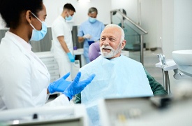 happy man talking to dentist about dental implants in River Ridge