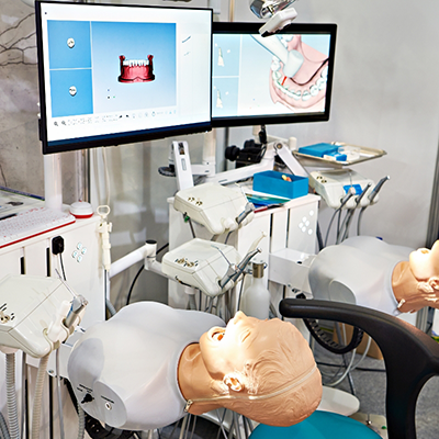 Dental school classroom with dummies and monitors set up for treatment practice