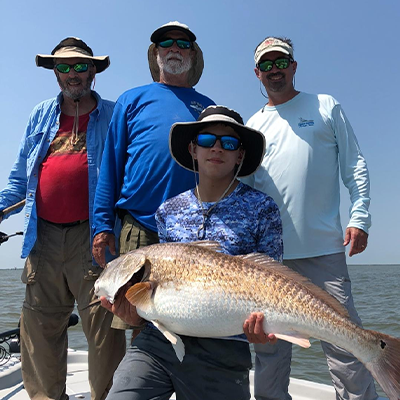 Four people on a boat with one holding a fish