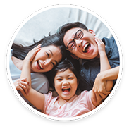 Little girl laughing with her parents on bed