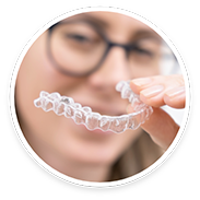 Woman with glasses holding a clear aligner