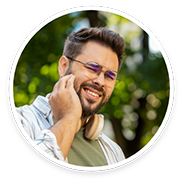 Bearded man with glasses rubbing jaw in pain