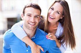 A young couple smiling and hugging.