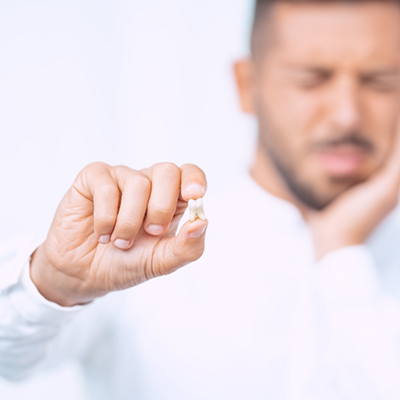 Man holding extracted tooth and rubbing jaw