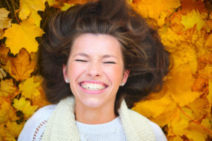 Woman smiling among autumn leaves