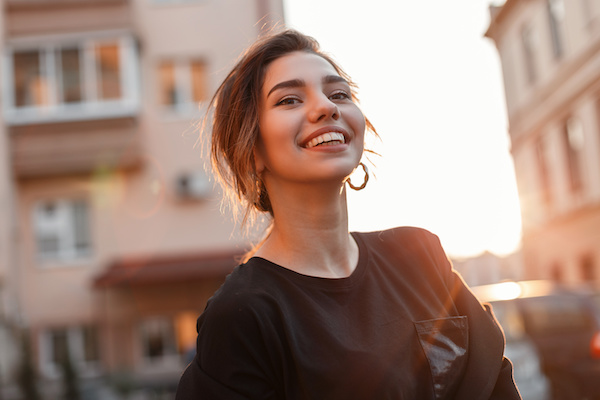 young woman smiling at sunset, cityscape behind her